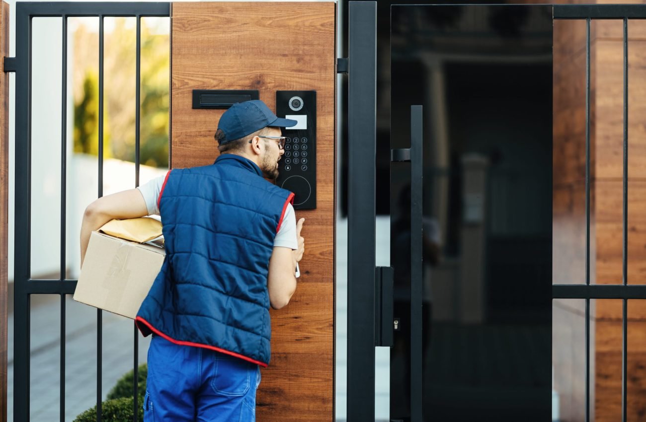 back-view-deliverer-ringing-intercom-gate-customer-s-house-while-delivering-packages (1)